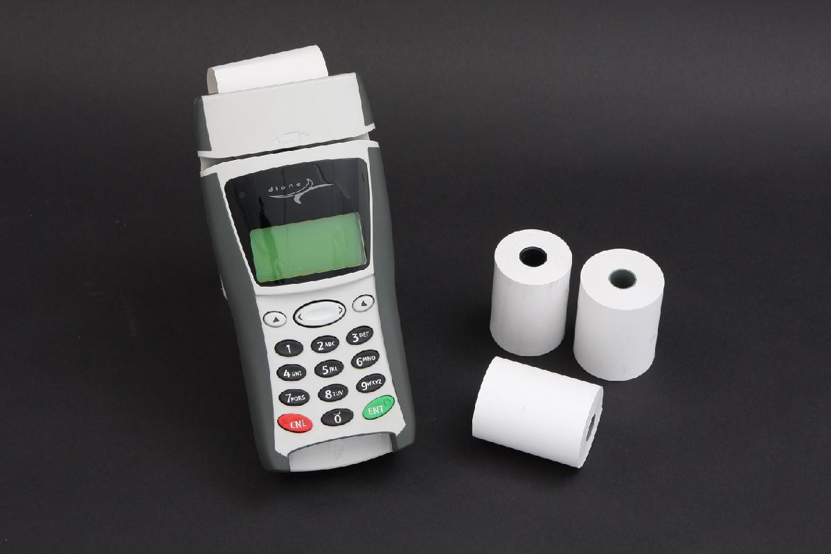 Thermal receipt rolls beside a card payment terminal